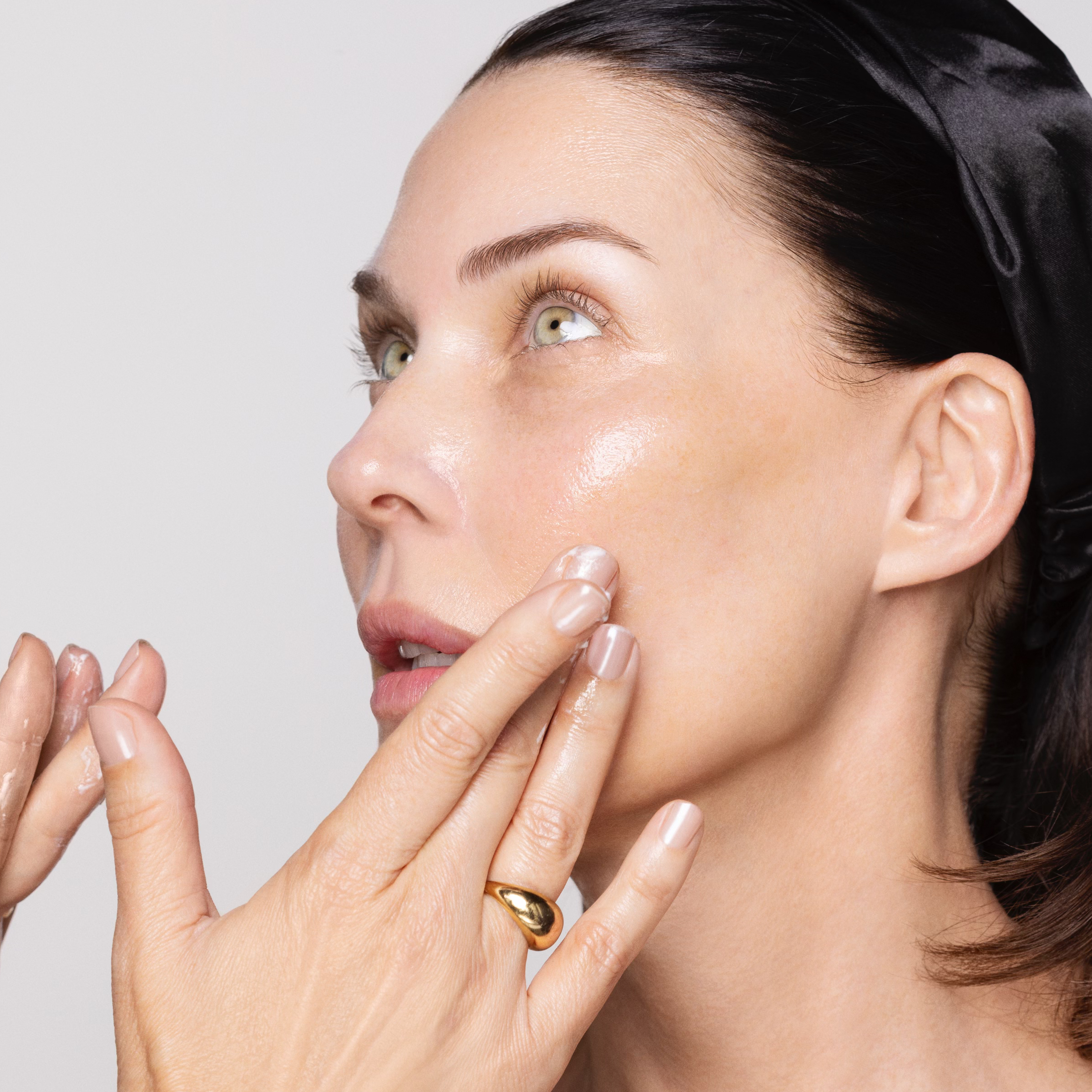 Brunette model with 2 hands touching face glowing skin.